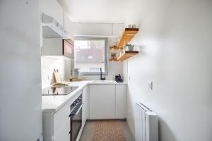 a small kitchen with white cabinets and a window at Joli nid douillet proche de Paris in Boulogne-Billancourt
