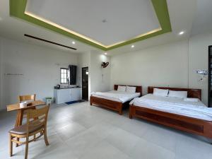a bedroom with two beds and a desk and a chair at OYO 1064 Phat Tai Hotel And Apartment in Da Nang