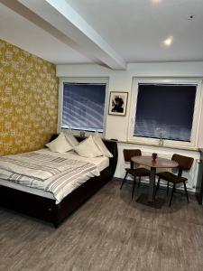 a bedroom with a bed and a table and two windows at Tondose Apartment in Dortmund