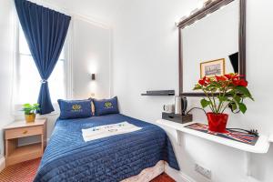 1 dormitorio con cama azul y espejo en Jubilee Hotel Victoria, en Londres