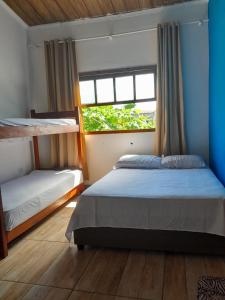 a bedroom with two bunk beds and a window at Hostel Canto da Alegria in Itanhaém