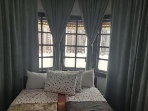 a bed with pillows in a room with windows at Gnezdo Studio Apart in Shipka