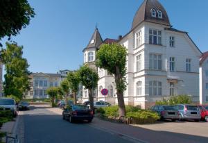 duży biały budynek z samochodami zaparkowanymi na parkingu w obiekcie Ahlbeck, Schloss Hohenzollern - WG 20 - OG 1 w mieście Ahlbeck