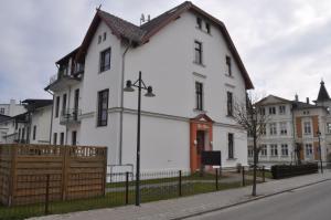 ein weißes Haus mit einem Zaun davor in der Unterkunft Ahlbeck, Villa Medici - seitlicher Meerblick in Ahlbeck