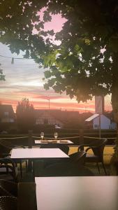 eine Gruppe von Tischen und Stühlen mit einem Sonnenuntergang im Hintergrund in der Unterkunft Uhldinger-Hof in Uhldingen-Mühlhofen