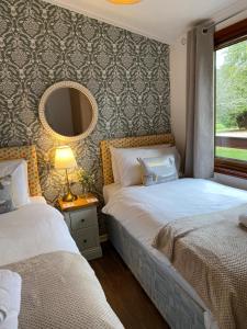 a bedroom with two beds and a mirror at Walled Garden Lodges Loch Lomond in Balloch