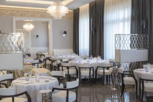 a dining room with white tables and chairs and a chandelier at Hotel Grande Italia in Chioggia