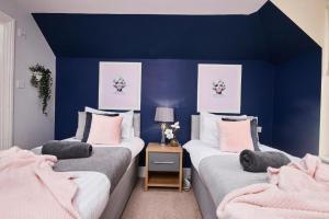 two beds in a room with blue walls at The Moss x Monroe Suite - In Central Bath in Bath