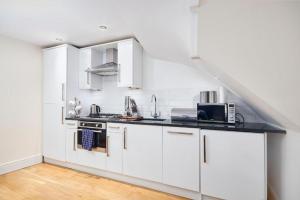 una cocina blanca con armarios blancos y fregadero en The Moss x Monroe Suite - In Central Bath, en Bath