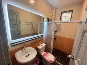 a bathroom with a sink and a toilet and a mirror at Eden Height Cozy & Spacious Condominiums in City of Kuching in Kuching