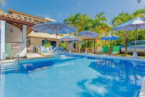 グアラジュバにあるGB19 Casa 7 Quartos a 50m da Praia - Guarajubaの青いパラソルと椅子付きのスイミングプール