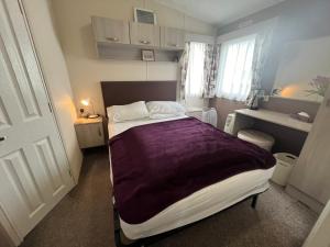 a bedroom with a bed with a purple blanket on it at Heron, Sea View, Scratby - California Cliffs, Parkdean, sleeps 6, bed linen and towels included, pet free, onsite entertainment available in Scratby