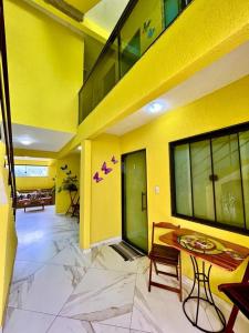 a room with a yellow wall with a table and chairs at POUSADA OHANA PARATY in Paraty