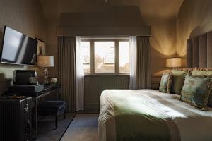 een slaapkamer met een bed, een raam en een televisie bij Althoff St James's Hotel & Club London in Londen