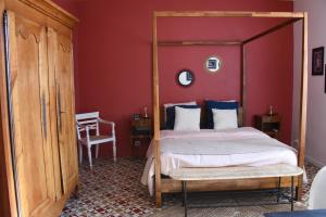 1 dormitorio con cama con dosel y pared roja en Mas Gardane en Pernes-les-Fontaines