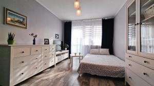 sypialnia z łóżkiem, komodą i oknem w obiekcie Przystań Bałtyk Apartment w Gdańsku