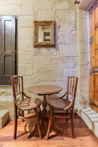 mesa de madera, 2 sillas, mesa y pared en Charming home with Stunning City Views in Birgu by 360 Estates, en Birgu
