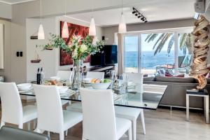 a dining room with a glass table and white chairs at Houghton Steps in Cape Town