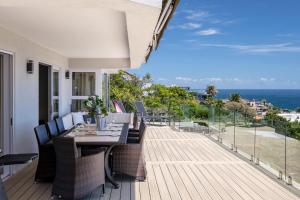 a dining table and chairs on a deck with the ocean at Houghton Steps in Cape Town