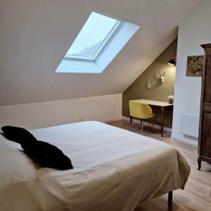 ein Schlafzimmer mit einem Bett und einem Dachfenster in der Unterkunft Le Colombier in Laon