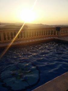 uma piscina de água com o pôr do sol no fundo em Villa Cariño em Sant Genís de Palafolls