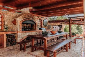 an outdoor kitchen with a stone fireplace and wooden benches at Talići Hill - Rustic Villas in Sutomore