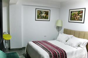 a bedroom with a bed and two pictures on the wall at New Apartment in Historic City Center in Cusco
