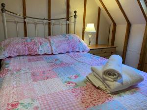 een bed met een quilt en een handdoek erop bij Barn Owl Cottage, The Welsh Reindeer Retreat, Ystradfach Farm , Llandyfaelog, Carmarthen , SA17 5NY in Carmarthen