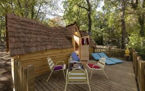 une terrasse en bois avec des chaises et une salle de jeux dans l'établissement Camping USHUAÏA Villages Au Bois Joli, à Andryes