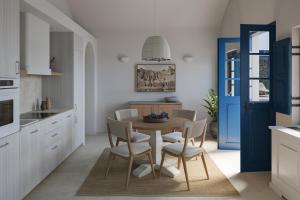 une cuisine avec une table et des chaises ainsi qu'une porte bleue dans l'établissement Vedema, a Luxury Collection Resort, Santorini, à Megalochori