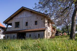 una casa vieja en un campo con un árbol en Razborca, en Mislinja