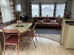 uma sala de estar com uma mesa e um sofá em Woodberry (Acorn Caravan Holidays Newquay) em Crantock