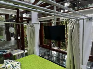 Schlafzimmer mit einem Bett und einem Fenster mit einem TV in der Unterkunft Casa de Vidro - Vila Mágica in Bueno Brandão