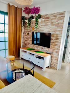 ein Wohnzimmer mit einem TV an einer Backsteinwand in der Unterkunft Apartment Laura in Puerto Rico with ocean view free WiFi and Nespresso coffee in Puerto Rico de Gran Canaria