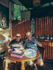 two men sitting at a table with a cake at Homestay Sente in Munduk
