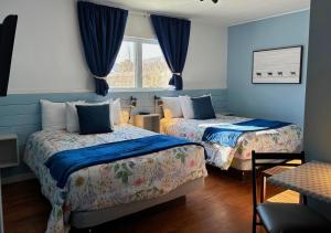 2 camas en una habitación con paredes azules en Aux Portes du Soleil, en Baie-Saint-Paul