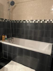 a bath tub in a bathroom with a tile wall at 如家公寓1 in Strasbourg