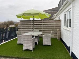 a patio with a table and chairs and an umbrella at Contemporary Holiday apartment in Perranporth