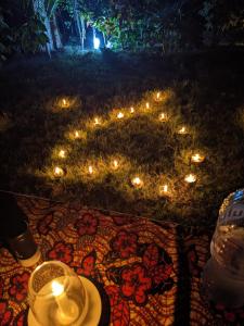kua garden cottage في Utende: طاولة مع الشموع وصحن على الأرض