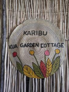 um sinal no lado de uma parede de bambu em kua garden cottage em Utende