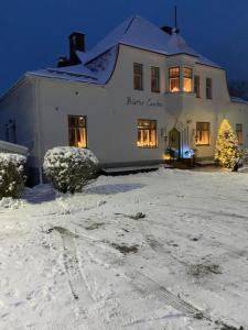 a white house with a christmas tree in the snow at Vanha Kanttorila ,Huone B pohjakerroksessa in Lovisa