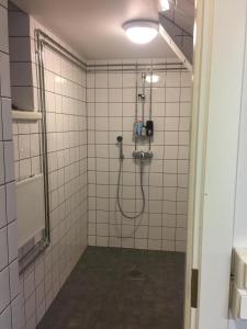 a bathroom with a shower with white tiles at Vanha Kanttorila ,Huone B pohjakerroksessa in Lovisa