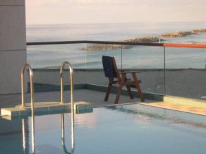 a swimming pool with a chair sitting on a balcony at Marina towers in Herzelia 