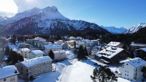 a town covered in snow with a mountain in the background at Chesa La Montanella - Ferienwohnung, Maloja in Maloja