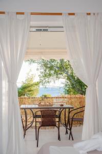 eine Terrasse mit einem Tisch, Stühlen und einem Fenster in der Unterkunft Heracles Guesthouse in Rovies