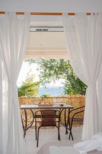 a patio with a table and chairs and a window at Heracles Guesthouse in Rovies