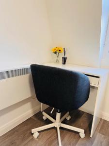 Cozy Studio in Maidstone Town Centre في Kent: كرسي يجلس في مكتب مع إناء من الزهور