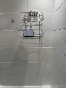 baño con estante sobre una pared de azulejos blancos en Well-preserved cozy1BR flat in LCY with free parking en Londres