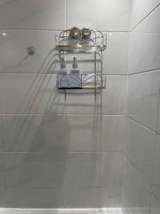baño con estante sobre una pared de azulejos blancos en Well-preserved cozy1BR flat in LCY with free parking, en Londres