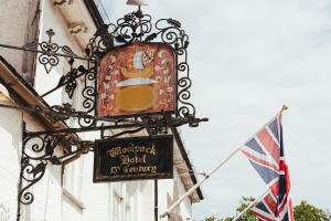 um sinal na lateral de um edifício com uma bandeira em The Woolpack Hotel em Tenterden